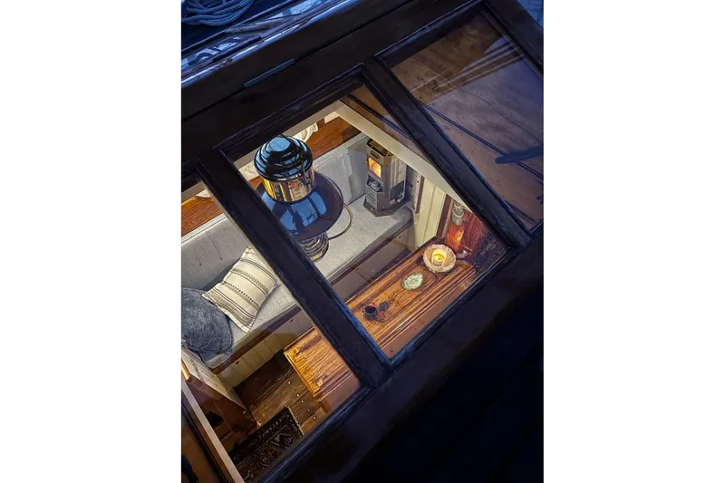 Slide: The Image of Cozy interior of 2004 Custom Luke Powell Pilot Cutter, featuring a lantern and wooden furnishings. - 18