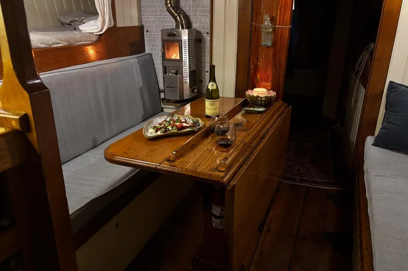 Slide: The Image of Cozy interior of 2004 Custom Luke Powell Pilot Cutter with dining area and wood stove. - 22