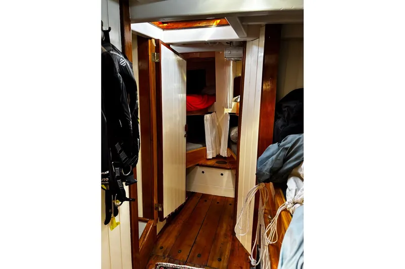 Slide: The Image of Cozy interior of 2004 Custom Luke Powell Pilot Cutter with wooden flooring and storage. - 24