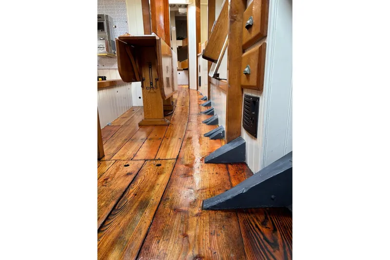 Slide: The Image of Interior of 2004 Custom Luke Powell Pilot Cutter with polished wooden flooring and cabinetry. - 25