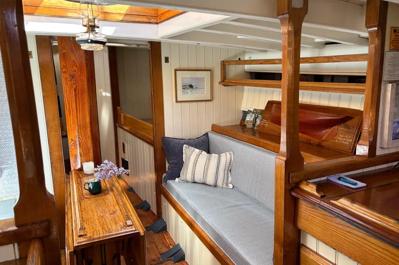 Slide: The Image of Interior of 2004 Custom Luke Powell Pilot Cutter with wooden furnishings and cozy seating area. - 26