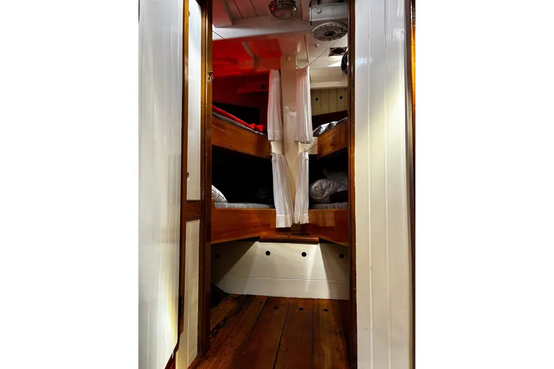 Slide: The Image of Interior of 2004 Custom Luke Powell Pilot Cutter with wooden bunk beds and cozy cabin design. - 28