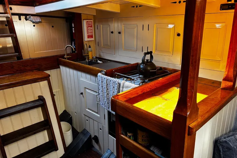 Slide: The Image of Cozy wooden interior of 2004 Luke Powell Pilot Cutter kitchen with stove and sink. - 31