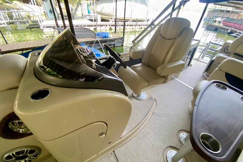 Slide: The Image of 2014 AquaPatio 220 WB boat interior with helm, captain's chair, and table. - 12