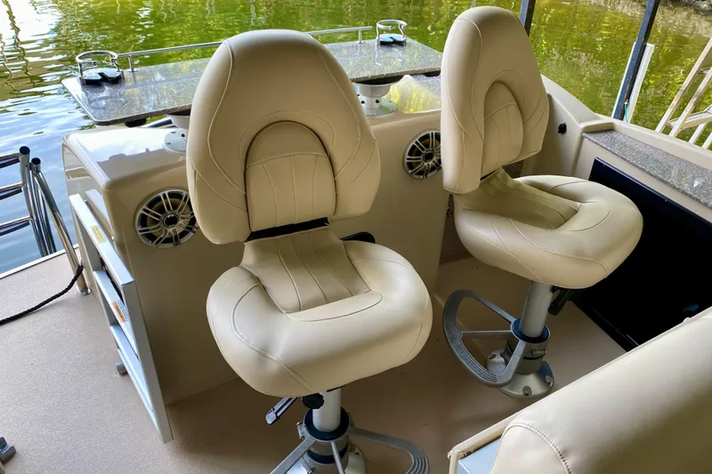 Slide: The Image of 2014 AquaPatio 220 WB boat interior with two beige captain chairs and water view. - 16