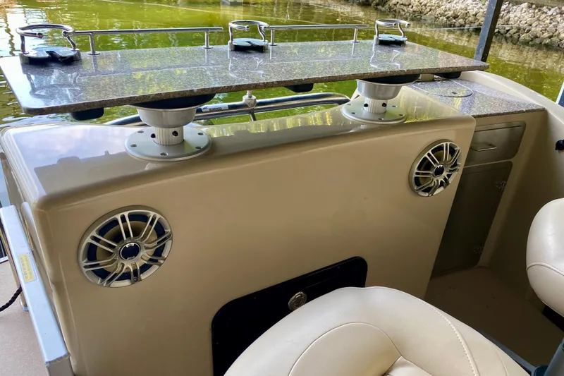 Slide: The Image of 2014 AquaPatio 220 WB boat interior with speakers and countertop, docked by the water. - 22