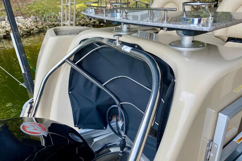Slide: The Image of 2014 AquaPatio 220 WB boat with stainless steel railing and motor, docked by a rocky shore. - 24