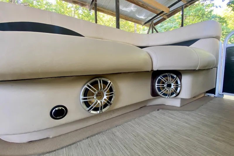 Slide: The Image of 2014 AquaPatio 220 WB boat interior with beige seating and built-in speakers. - 9