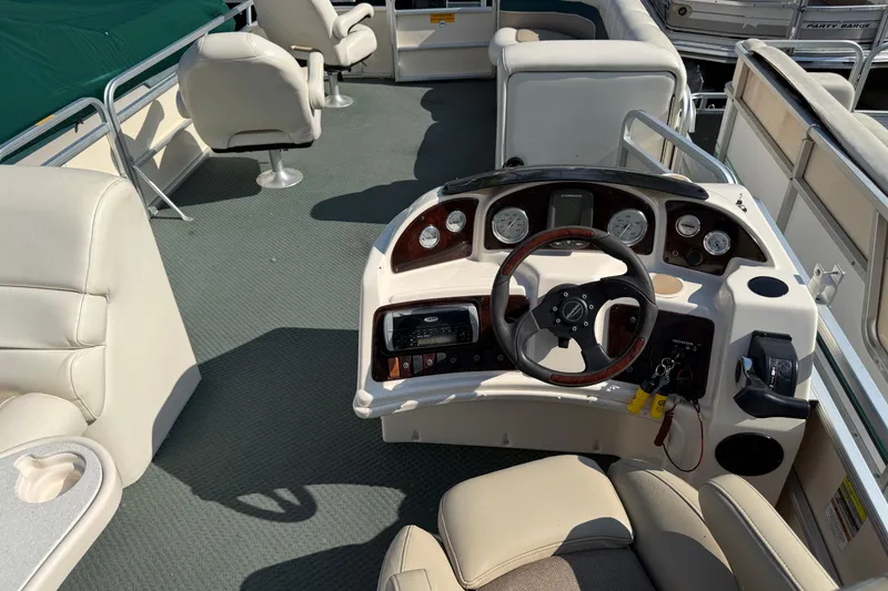 Slide: The Image of 2004 AquaPatio 240RE boat interior with steering console and seating arrangement. - 24