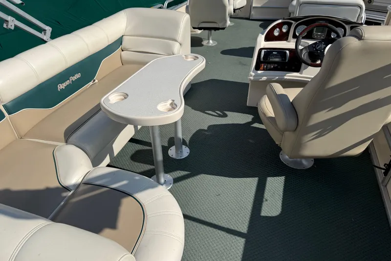 Slide: The Image of 2004 AquaPatio 240RE boat interior with seating, table, and steering console. - 25