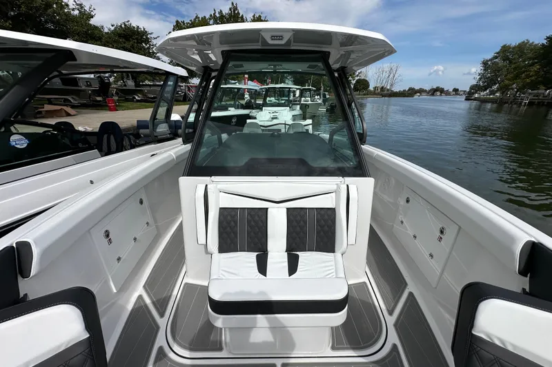 Slide: The Image of 2026 Monterey Elite 30 OB boat interior with sleek seating and modern design on a calm waterway. - 13
