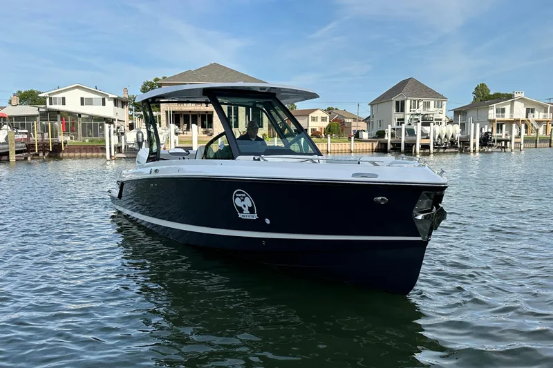 Slide: The Image of 2026 Monterey Elite 30 OB boat on calm water near residential docks. - 18