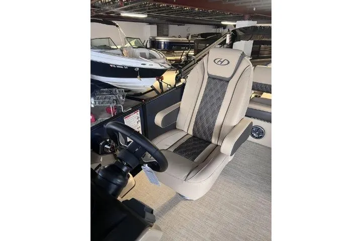 Slide: The Image of 2024 Harris Sunliner 230 boat interior with luxurious captain's chair and steering wheel. - 11