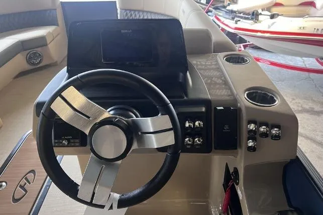 Slide: The Image of 2024 Harris Sunliner 230 boat dashboard with steering wheel and control panel. - 12