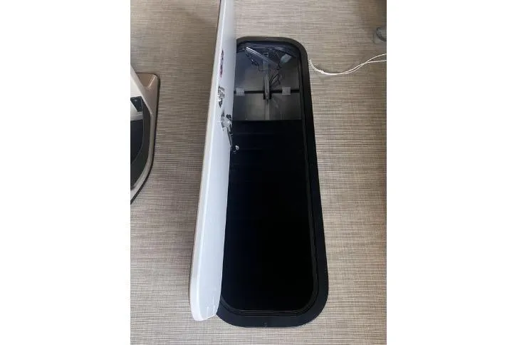 Slide: The Image of 2024 Harris Sunliner 230 storage compartment with open hatch on a textured floor. - 17