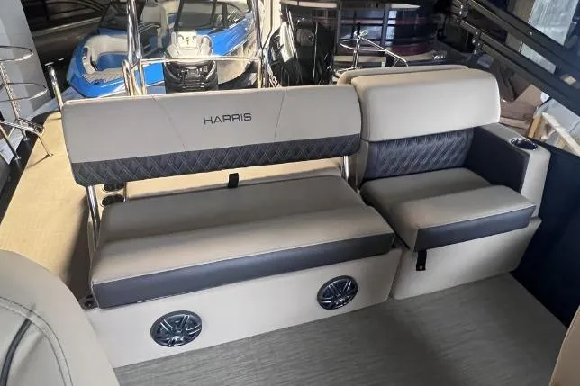 Slide: The Image of 2024 Harris Sunliner 230 boat interior with beige and black seating, featuring built-in speakers. - 18