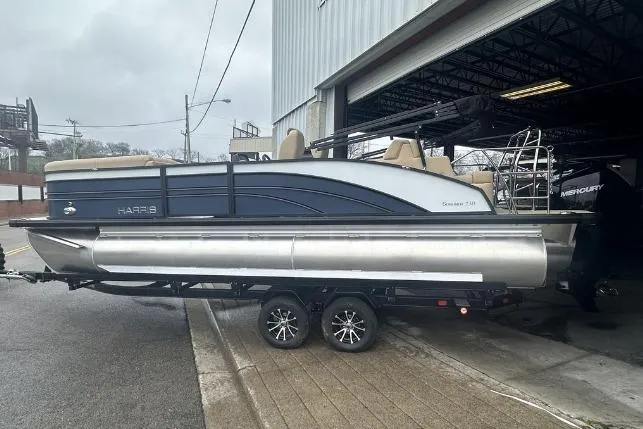 Slide: The Image of 2024 Harris Sunliner 230 pontoon boat on trailer outside a garage. - 2