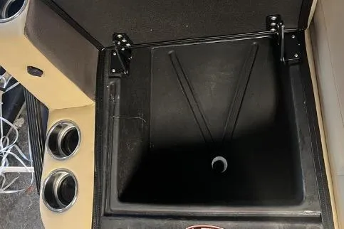 Slide: The Image of 2024 Harris Sunliner 230 storage compartment with cup holders and black interior. - 21