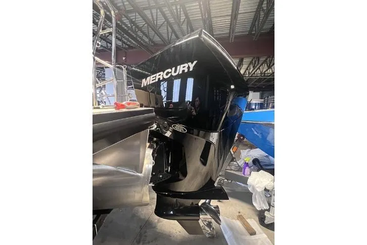 Slide: The Image of 2024 Harris Sunliner 230 with Mercury outboard engine in a warehouse setting. - 23