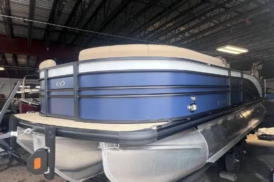 Slide: The Image of 2024 Harris Sunliner 230 pontoon boat in a warehouse, featuring a sleek blue design. - 3