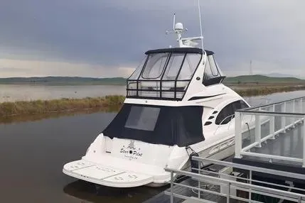 Slide: The Image of 2005 Sea Ray 420 Sedan Bridge yacht docked by a serene lakeside. - 1