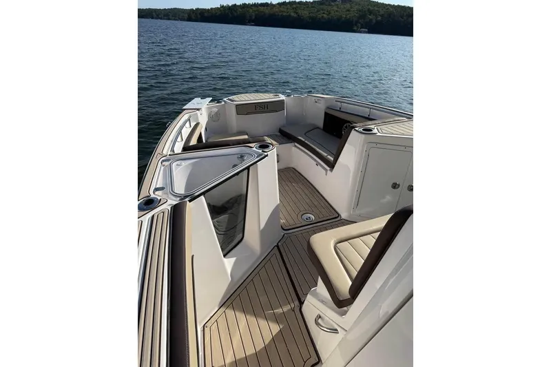 Slide: The Image of 2023 Yamaha 252 FSH boat interior with seating and storage on a calm lake. - 15