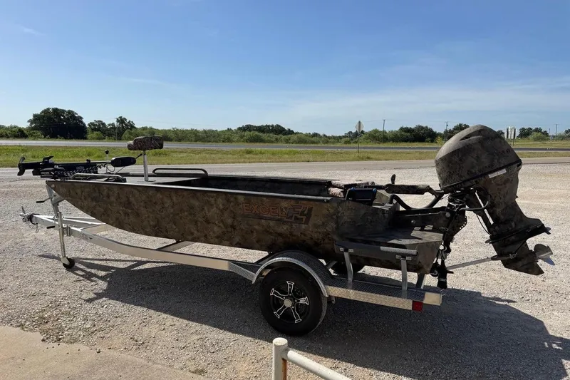 Slide: The Image of 2023 Excel 1751V4M boat on trailer, camo design, parked outdoors. - 4