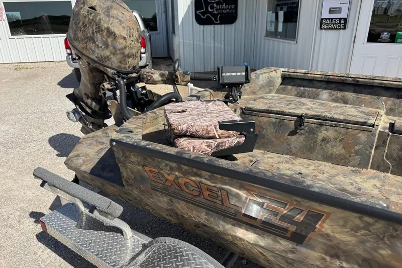 Slide: The Image of Camouflage-patterned 2023 Excel 1751V4M boat with motor, parked outside a service shop. - 9