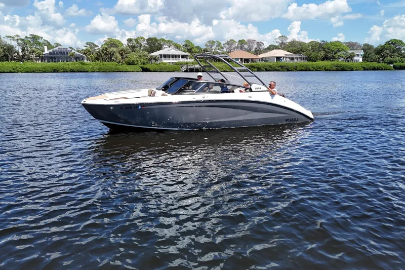 Slide: The Image of 2021 Yamaha Boats 252S cruising on a sunny day with scenic waterfront homes. - 22