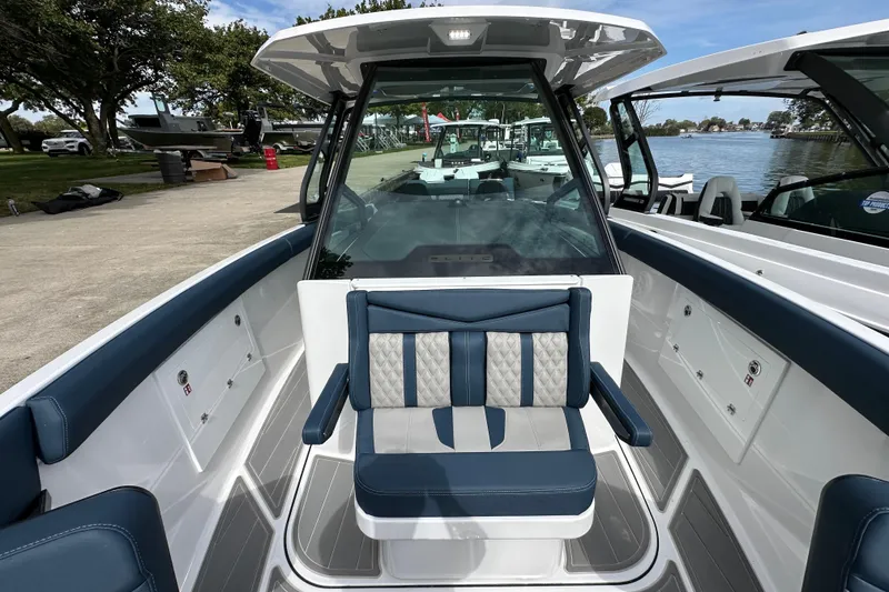 Slide: The Image of 2026 Monterey Elite 30 OB boat interior with blue and white seating, docked by a scenic lake. - 14