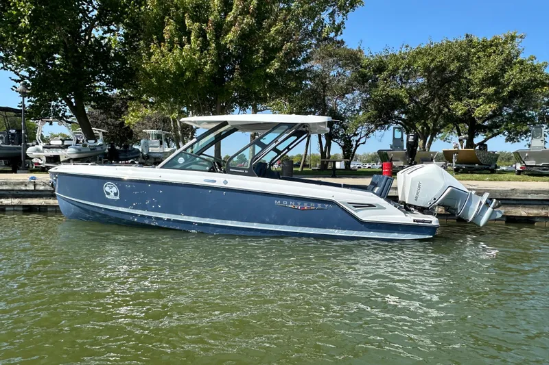 Slide: The Image of 2026 Monterey Elite 30 OB boat docked on a sunny day, surrounded by trees. - 2