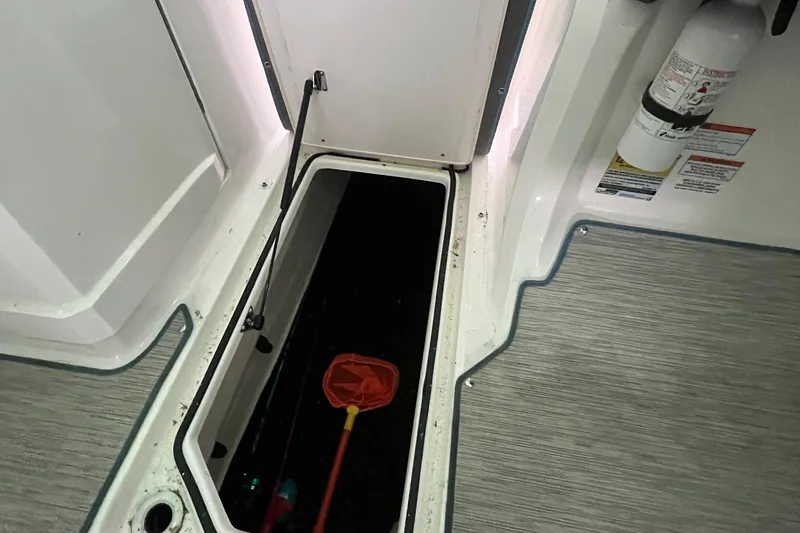 Slide: The Image of Open storage compartment on 2016 Regal 22 FasDeck ESX boat with safety equipment. - 18