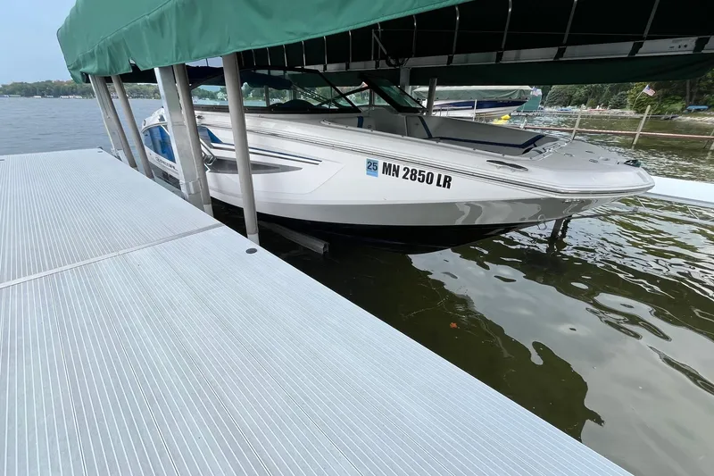 Slide: The Image of 2016 Regal 22 FasDeck ESX boat docked under a green canopy on a lake. - 4
