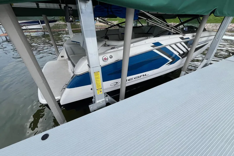 Slide: The Image of 2016 Regal 22 FasDeck ESX boat docked on a lake under a green canopy. - 5