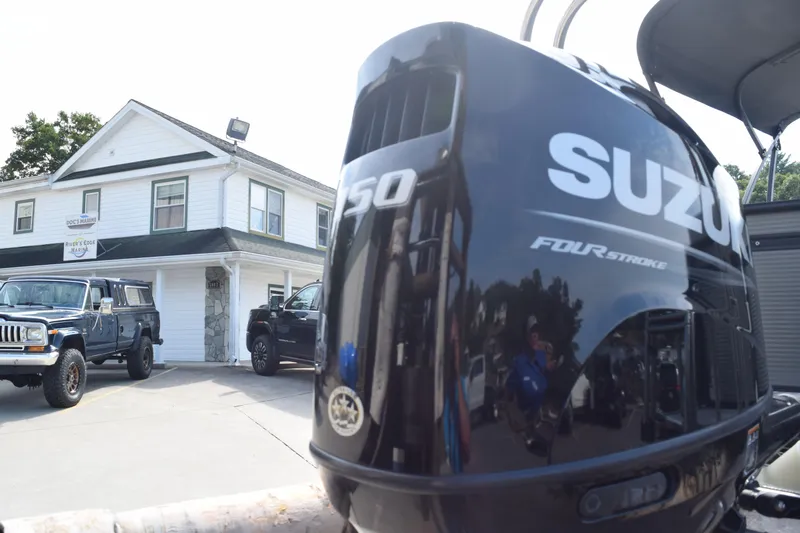 Slide: The Image of Outdoor scene with Suzuki outboard motor, vehicles, and a building labeled "River's Edge Marina." - 5