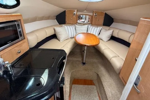 Slide: The Image of 2013 Glastron GS 289 cabin interior with kitchenette, seating area, and wooden table. - 10