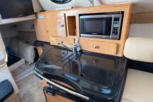 Slide: The Image of 2013 Glastron GS 289 boat interior with kitchenette, microwave, and sink. - 11