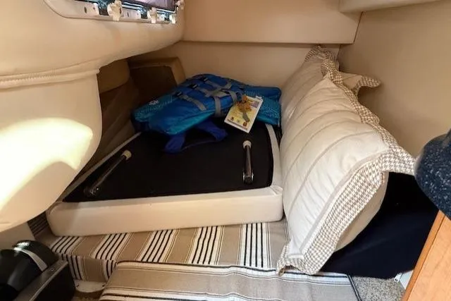 Slide: The Image of 2013 Glastron GS 289 cabin interior with life jacket, pillows, and striped flooring. - 12