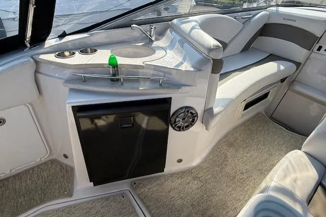 Slide: The Image of 2013 Glastron GS 289 boat interior with seating, mini fridge, and sink area. - 7