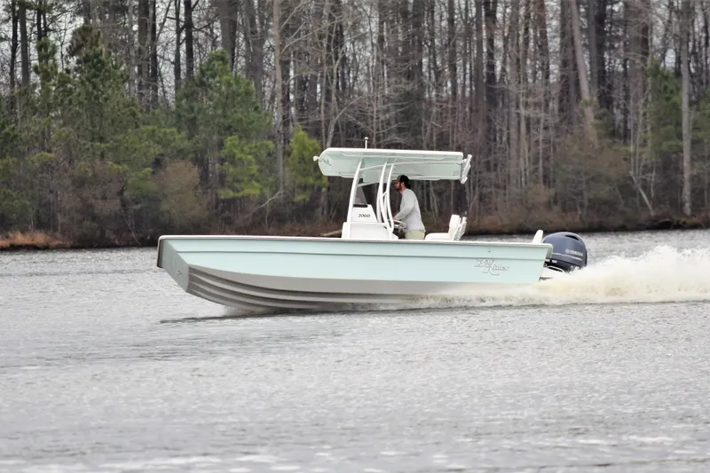 Slide: The Image of 2024 KenCraft 2060 Bay Rider Skiff cruising on a lake with forested background. - 6