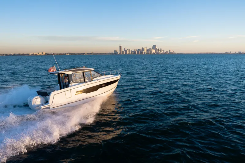 Slide: The Image of 2026 Jeanneau NC 895 Series 2 cruising on open water with city skyline in background. - 12