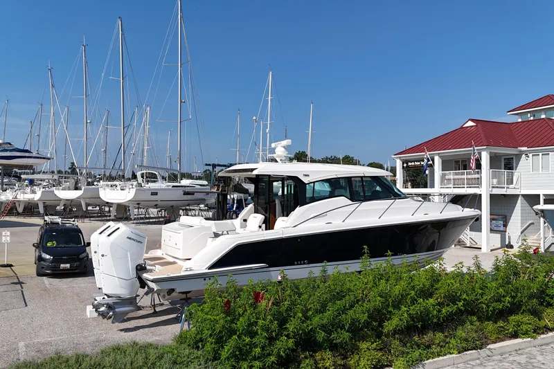 Slide: The Image of 2026 Tiara Yachts 43 LE docked at marina with sailboats and clubhouse. - 2