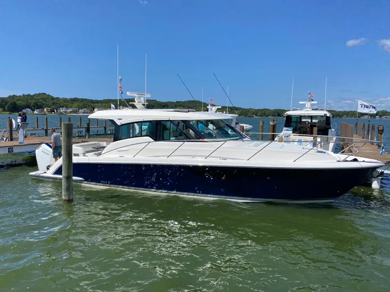 Slide: The Image of 2025 Tiara Yachts 43 LE docked in a marina, blue hull, sunny day. - 3