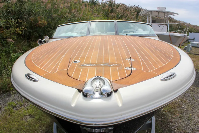 The Image of 2017 Chris-Craft Capri 27 boat with elegant wooden deck, parked outdoors. - 0