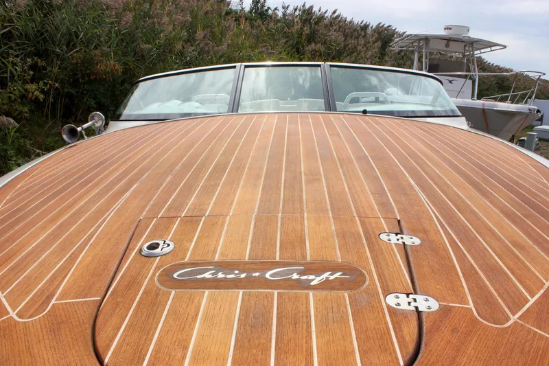 Slide: The Image of 2017 Chris-Craft Capri 27 boat on trailer, parked outdoors near vegetation. - 14