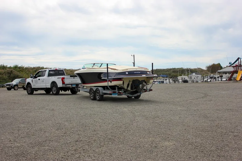 Slide: The Image of 2017 Chris-Craft Capri 27 boat on trailer outside a large garage. - 2
