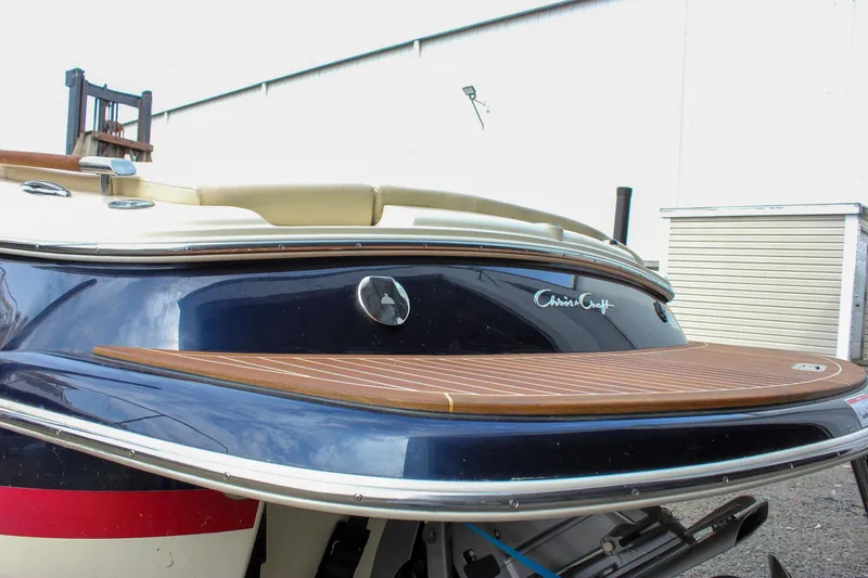 Slide: The Image of 2017 Chris-Craft Capri 27 boat rear view with wooden deck and logo. - 20