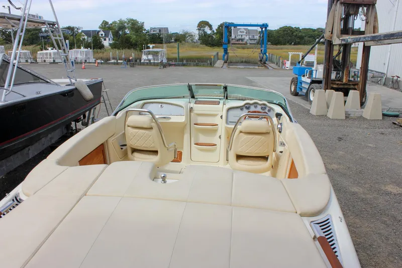 Slide: The Image of 2017 Chris-Craft Capri 27 boat on trailer, parked outdoors near a warehouse. - 23