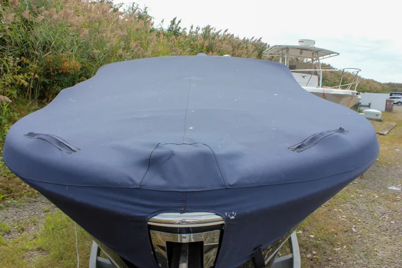 Slide: The Image of 2017 Chris-Craft Capri 27 boat on trailer, covered, near grassy area. - 8