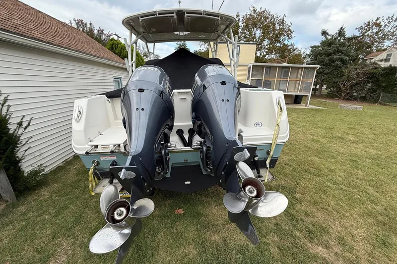 Slide: The Image of 2019 Sailfish 275 DC boat with dual outboard motors in a backyard setting. - 10